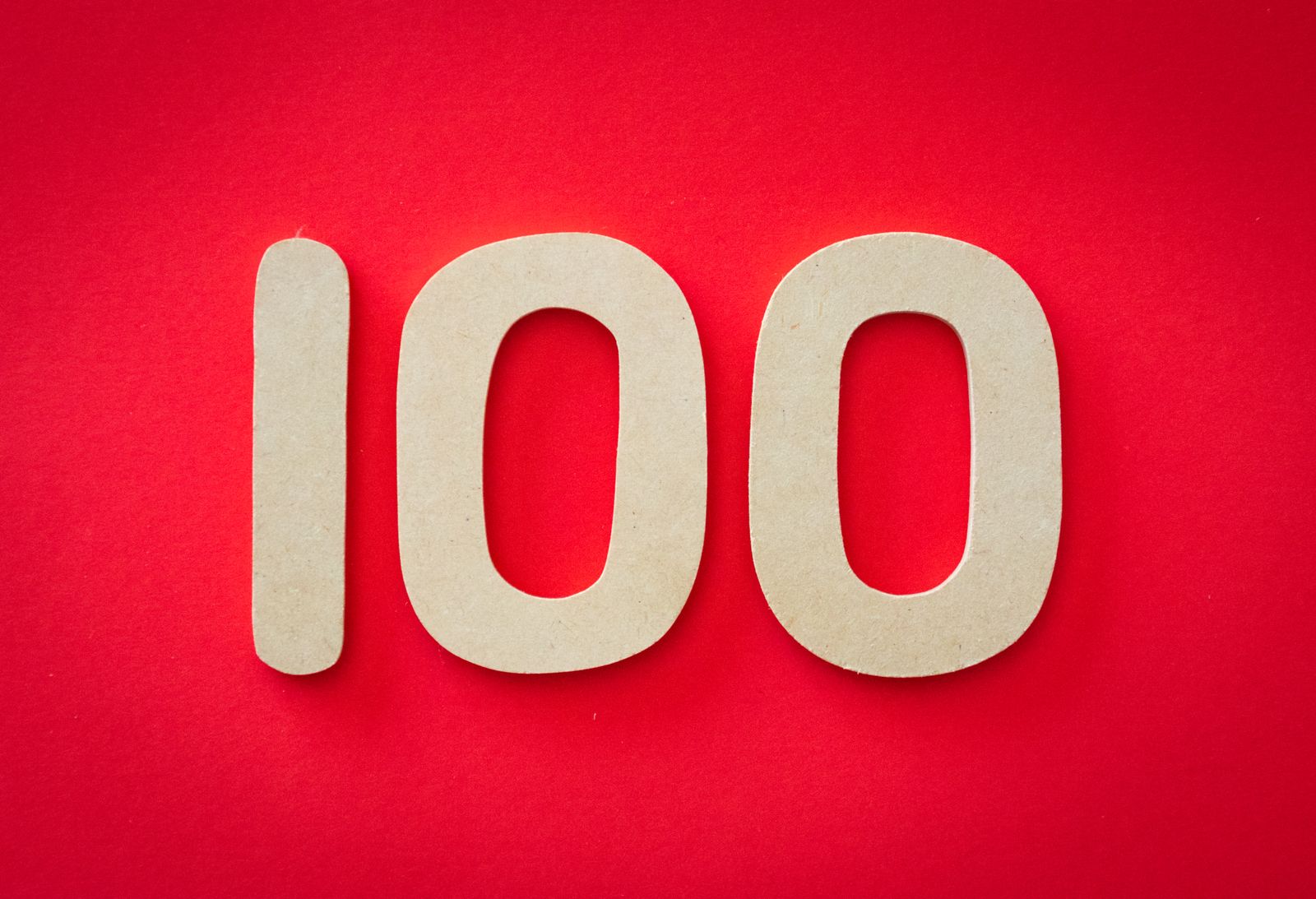 Le chiffre « 100 » est représenté par de grands chiffres découpés de couleur marron clair sur un fond rouge vif, évoquant le thème des « 100 questions d'entretien ».