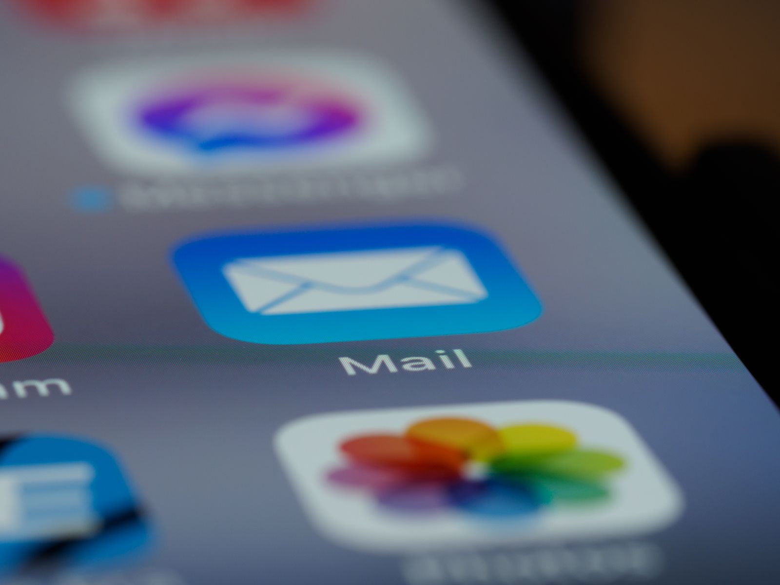 Gros plan sur l'écran d'un smartphone affichant plusieurs icônes d'applications, avec l'application Mail — idéale pour se relancer après un entretien d'alternance — au premier plan. L'enveloppe sur fond bleu se détache clairement, tandis qu'une partie de l'icône de l'application Photos est également visible.