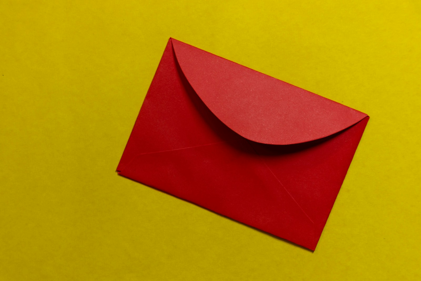 Une enveloppe rouge fermée, symbolisant une candidature spontanée, est placée sur un fond jaune vif.